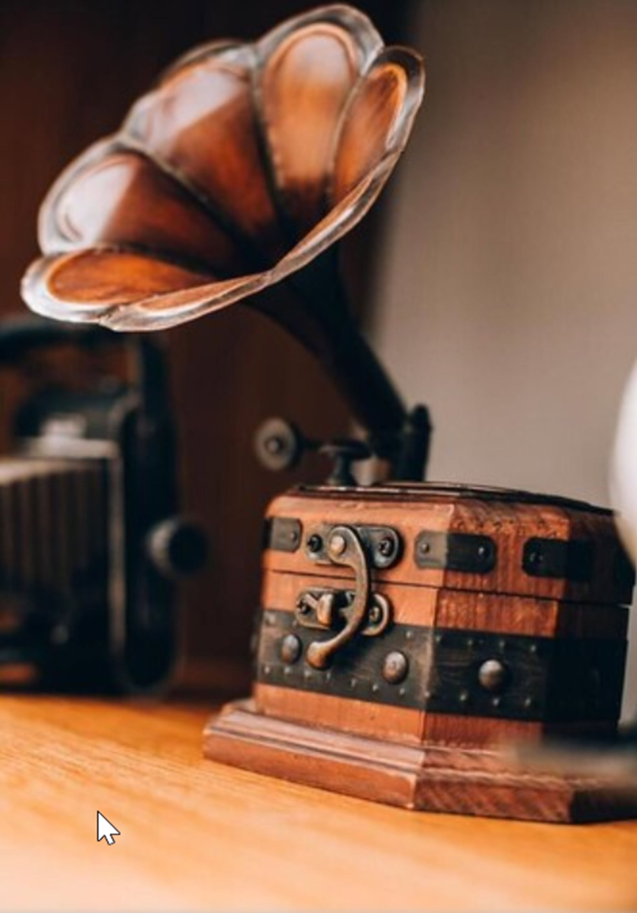 Un vieux gramophone posé sur une table en bois, avec une vieille radio en arrière-plan.
