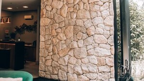 A modern lobby with a stone wall, green sofas, and a small table with a plant. - Villa Amistà Campos do Jordão (Campos do Jordão)