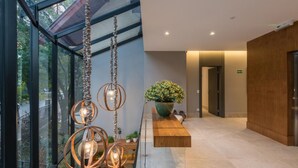 A modern interior with a glass wall, hanging pendant lights, a wooden bench, and a potted plant. - Villa Amistà Campos do Jordão (Campos do Jordão)