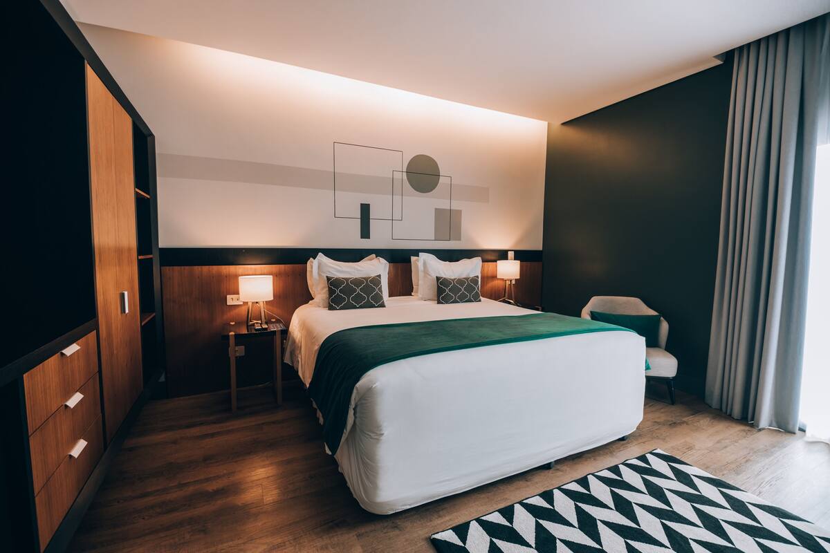 Una habitación de hotel moderna con una cama grande, mesitas de noche, un escritorio y una silla.