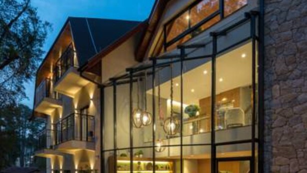 A modern hotel with a glass facade, multiple balconies, and a stone exterior. - Villa Amistà Campos do Jordão (Campos do Jordão)