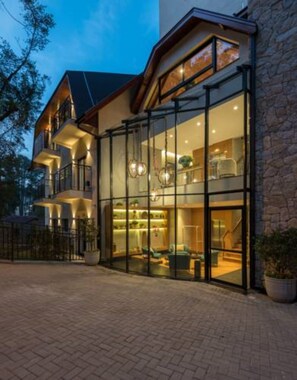 A modern hotel with a glass facade, multiple balconies, and a stone exterior. - Villa Amistà Campos do Jordão (Campos do Jordão)