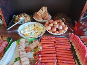 A table with various food items including sliced meat, eggs, bread, and sausages.