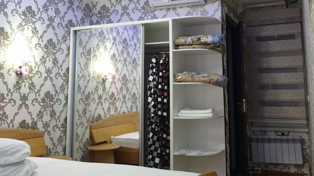 A bedroom with a bed, wardrobe, and a radiator. - Hotel Khiva (Tashkent)