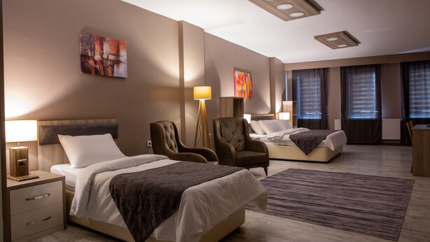 Ein Hotelzimmer mit zwei Betten, einem Schreibtisch, einem Stuhl und Bildern an den Wänden.