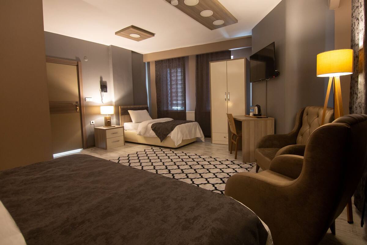 Une chambre d’hôtel moderne, dotée d’un grand lit, d’un bureau, d’une chaise et d’un téléviseur fixé au mur.