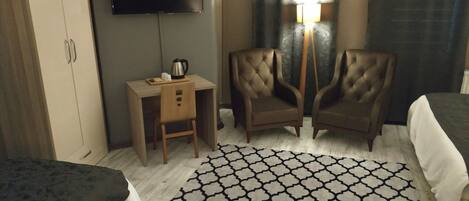 A hotel room with two beds, a desk with a chair, a television, and a patterned rug.