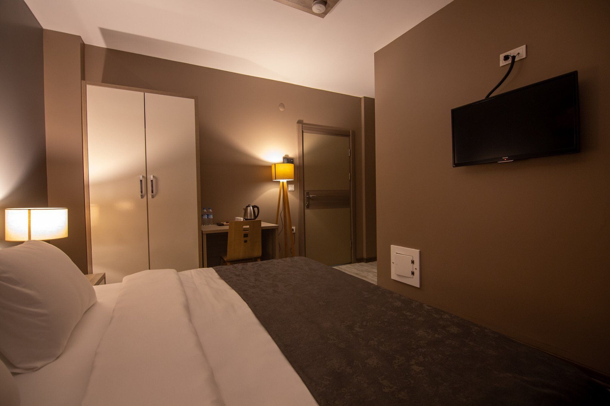 Une chambre d’hôtel équipée d’un lit, d’un bureau, d’une chaise, d’une lampe, d’une télévision et d’une armoire.