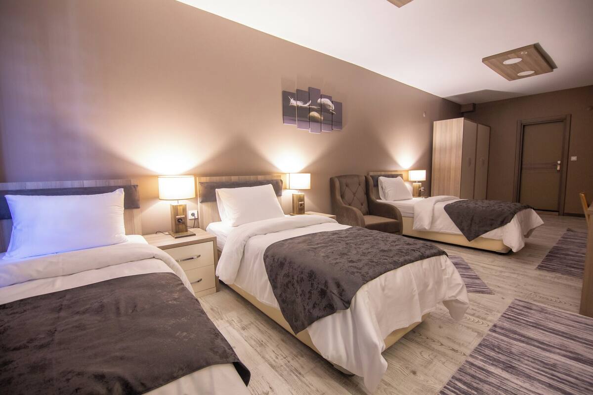 Une chambre d’hôtel avec trois lits, une armoire et une œuvre d’art accrochée au mur.