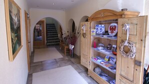 Un couloir avec des armoires en bois, un escalier et un tableau accroché au mur.