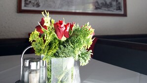 Une table avec un vase de roses rouges et un salier.
