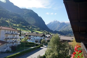 A mountain village with traditional buildings, a road, and a view of snow-capped mountains. - Pension Heidi (Kaprun)