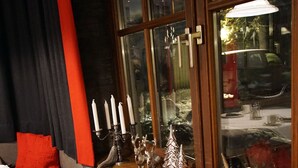 Un coin salon confortable avec un canapé et des fauteuils, une table agrémentée d’objets décoratifs et une fenêtre donnant sur la rue.