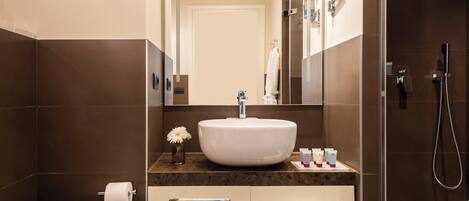 Un baño moderno con un lavamanos grande, un inodoro, una ducha y un espejo.