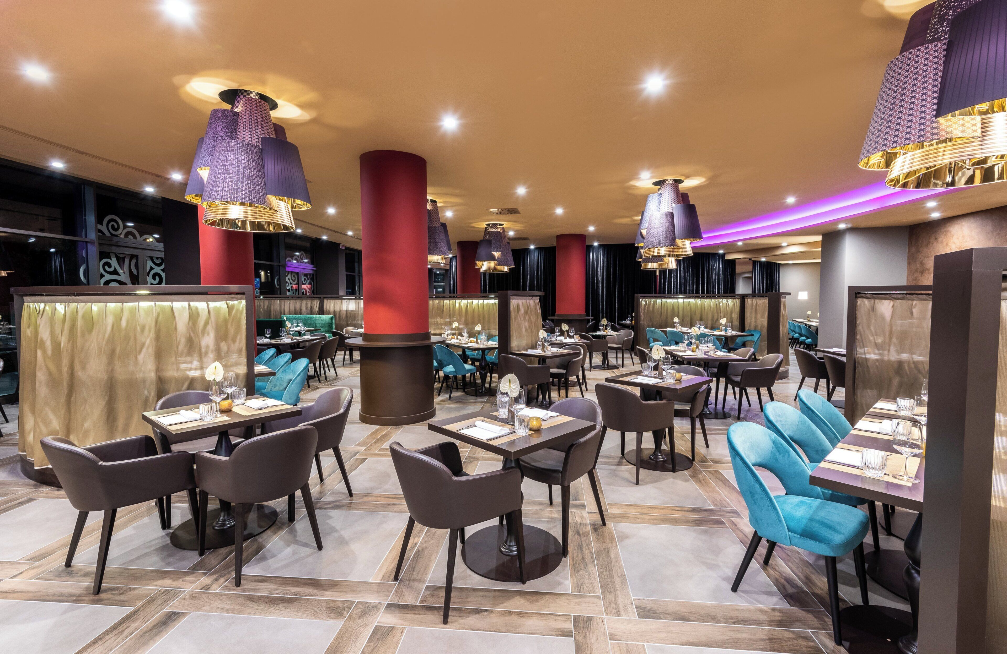 Un intérieur de restaurant moderne, doté de nombreuses tables, de chaises et d’éléments d’éclairage décoratifs.