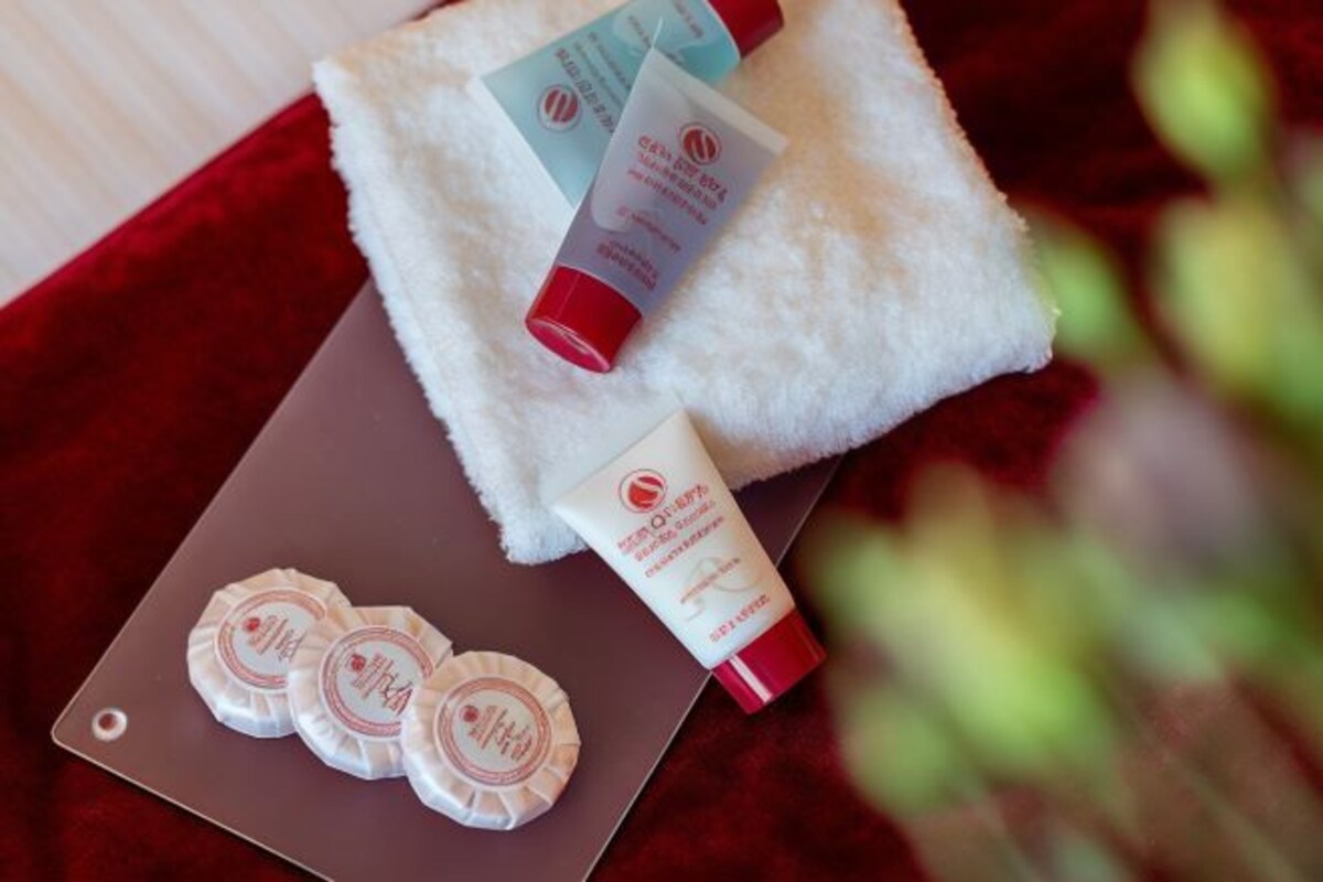 Une serviette blanche, deux produits de soins pour la peau et trois autocollants ronds sur une surface marron.