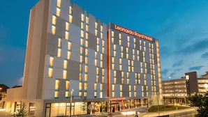 Un moderno edificio de hotel con un llamativo letrero que dice "Leonardo Royal Hotel", varios pisos y una fachada bien iluminada.