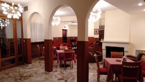 A dining area with marble flooring, red upholstered furniture, and a fireplace. - Hotel Viola (Caramanico Terme)