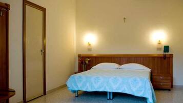 A bedroom with a bed, bedside tables, a wooden headboard, and wall-mounted lights.