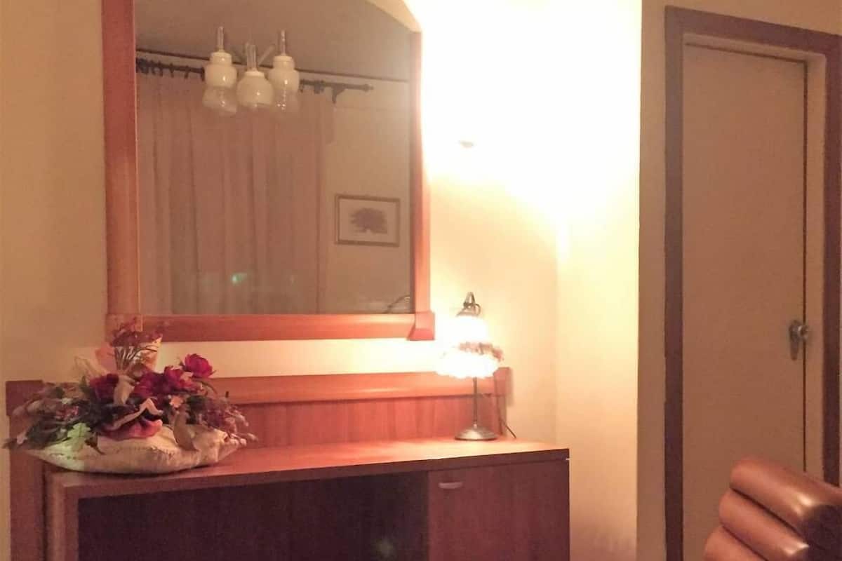 A room with a wooden desk, a chair, a mirror, and a lamp.