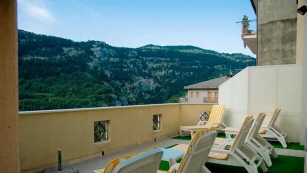 A rooftop terrace with lounge chairs and a table, overlooking a mountainous landscape. - Hotel Viola (Caramanico Terme)