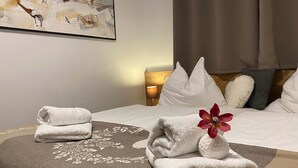 Cama bem arrumada com lençóis brancos e uma decoração de toalhas.