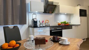 Cozinha moderna com mesa de jantar posta para dois, com bolo e xícaras de café.