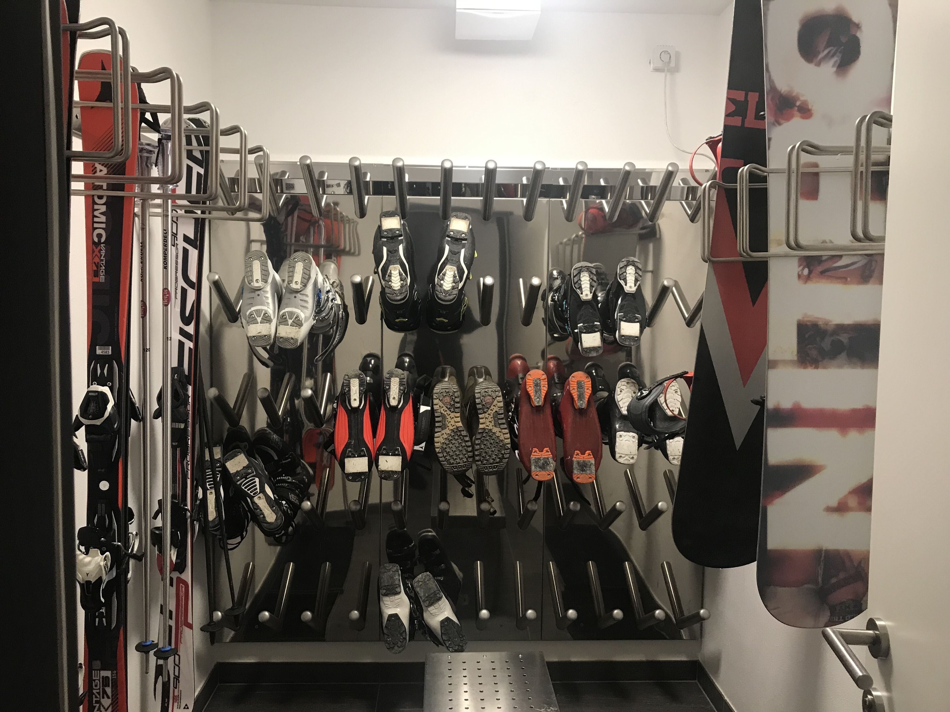 A ski rack with various skis and ski boots.