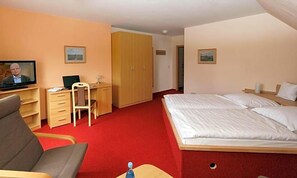 A hotel room with a bed, a desk with a chair, a television, and a wardrobe.
