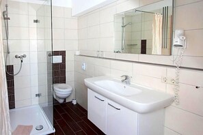 Une salle de bain moderne avec une douche à parois de verre, un lavabo blanc et des toilettes.