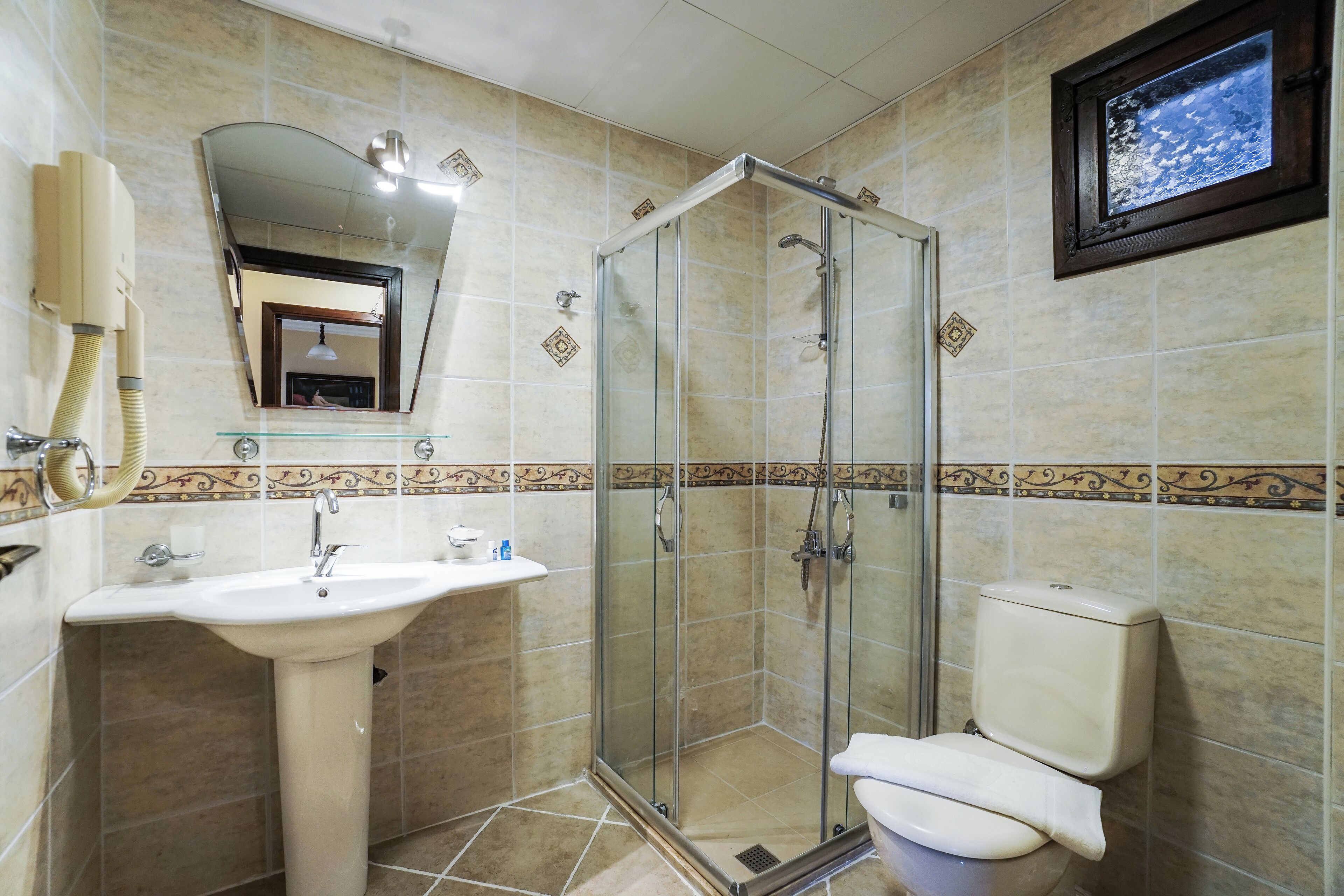 A bathroom with a glass-enclosed shower, a pedestal sink, and a toilet.