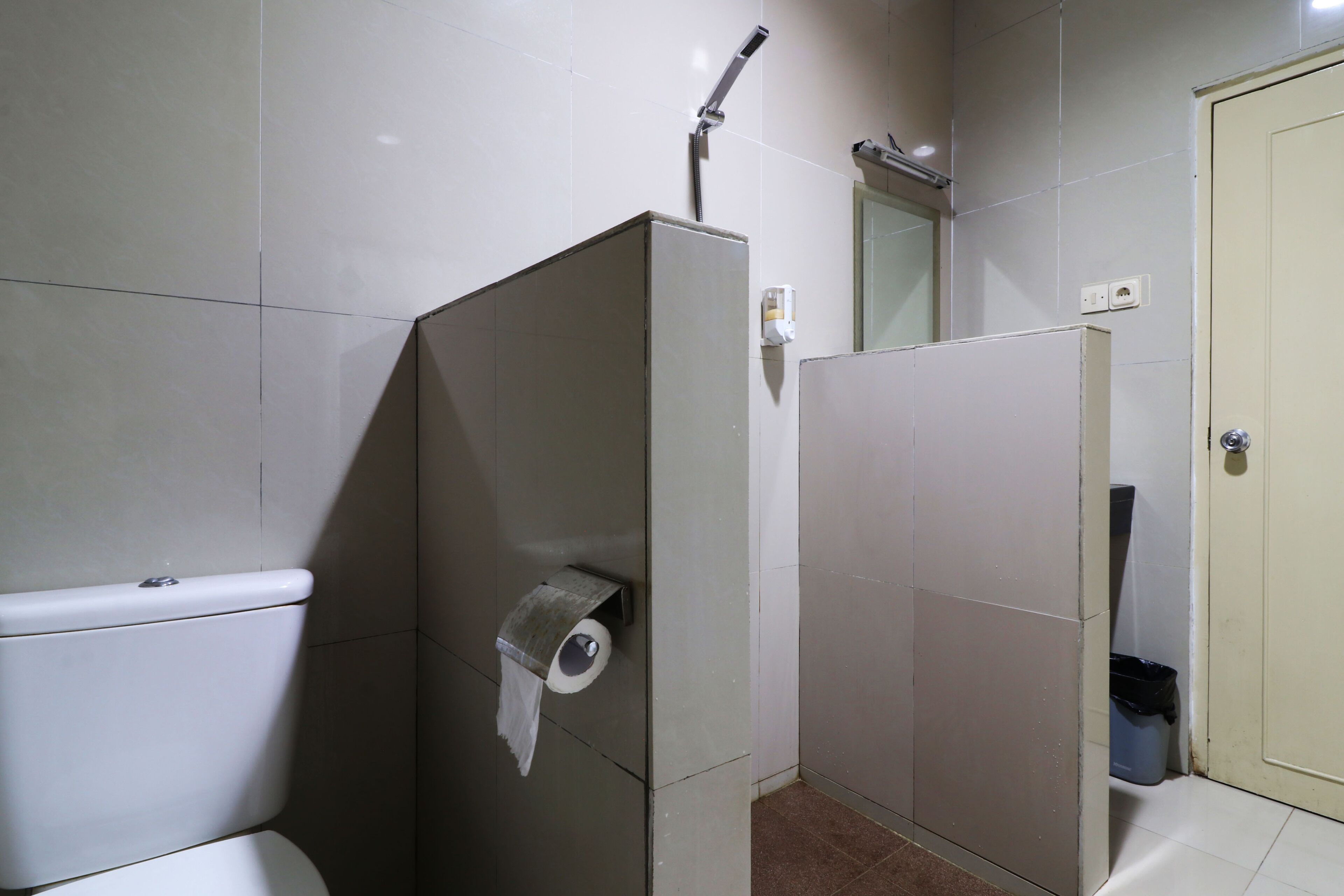 A small, compact bathroom with a toilet, a shower, and a sink.