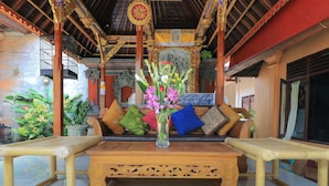 A traditional wooden bench with a vase of flowers in the center, surrounded by cushions. - Ubud Asri Homestay (Ubud)