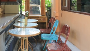 A small outdoor seating area with two round tables and four chairs, one of which is blue. - Ubud Asri Homestay (Ubud)
