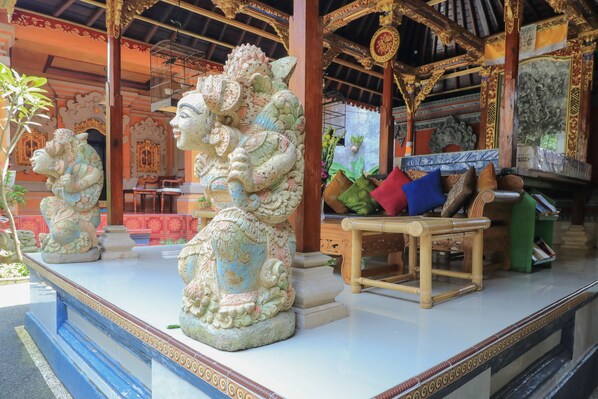 Interior de un templo con estatuas ornamentadas, un banco de madera y decoración tradicional.