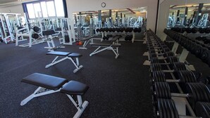 Een sportschool met diverse trainingsapparaten, waaronder banken, gewichten en krachtapparaten.