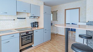 Een moderne keuken met lichtblauwe kastjes, een roestvrijstalen oven, een koffiezetapparaat en een bargedeelte met barkrukken.