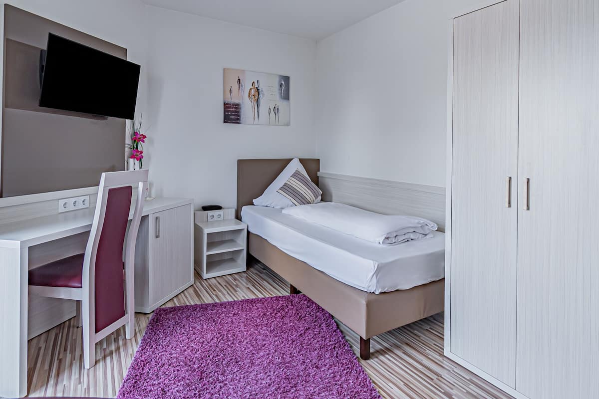 Quarto moderno com cama, escrivaninha, cadeira, guarda-roupa e uma obra de arte na parede.