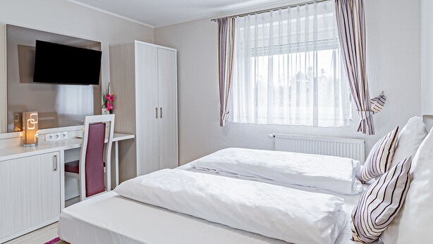 Een moderne slaapkamer met een bed, een bureau en een televisie.