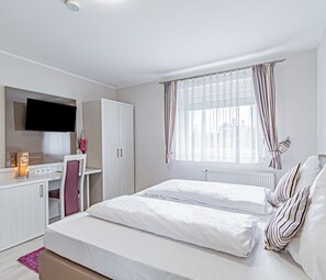 Un dormitorio moderno con una cama, un escritorio y un televisor.
