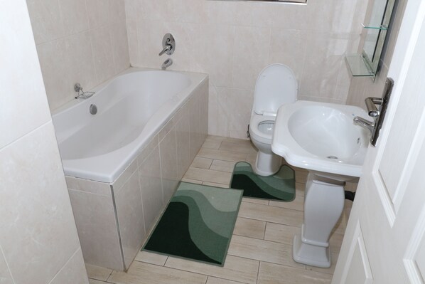 A bathroom with a bathtub, toilet, and sink. - Shiloh Luxury Lodge (Harare)