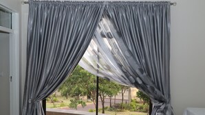 A room with a view through sheer curtains, a window, and a table. - Shiloh Luxury Lodge (Harare)