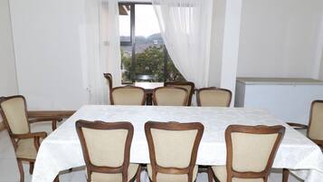A dining area with a table and chairs, a window with curtains, and a view of the outside.
