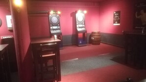 A bar area with two arcade machines, a wooden bar counter, and a red carpeted floor. - Apartment Osterstraße 123 (Hannover)