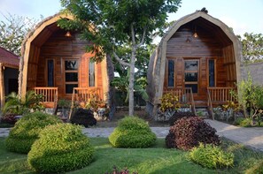 Dos cabañas de madera con balcones, rodeadas de jardines y árboles bien cuidados.