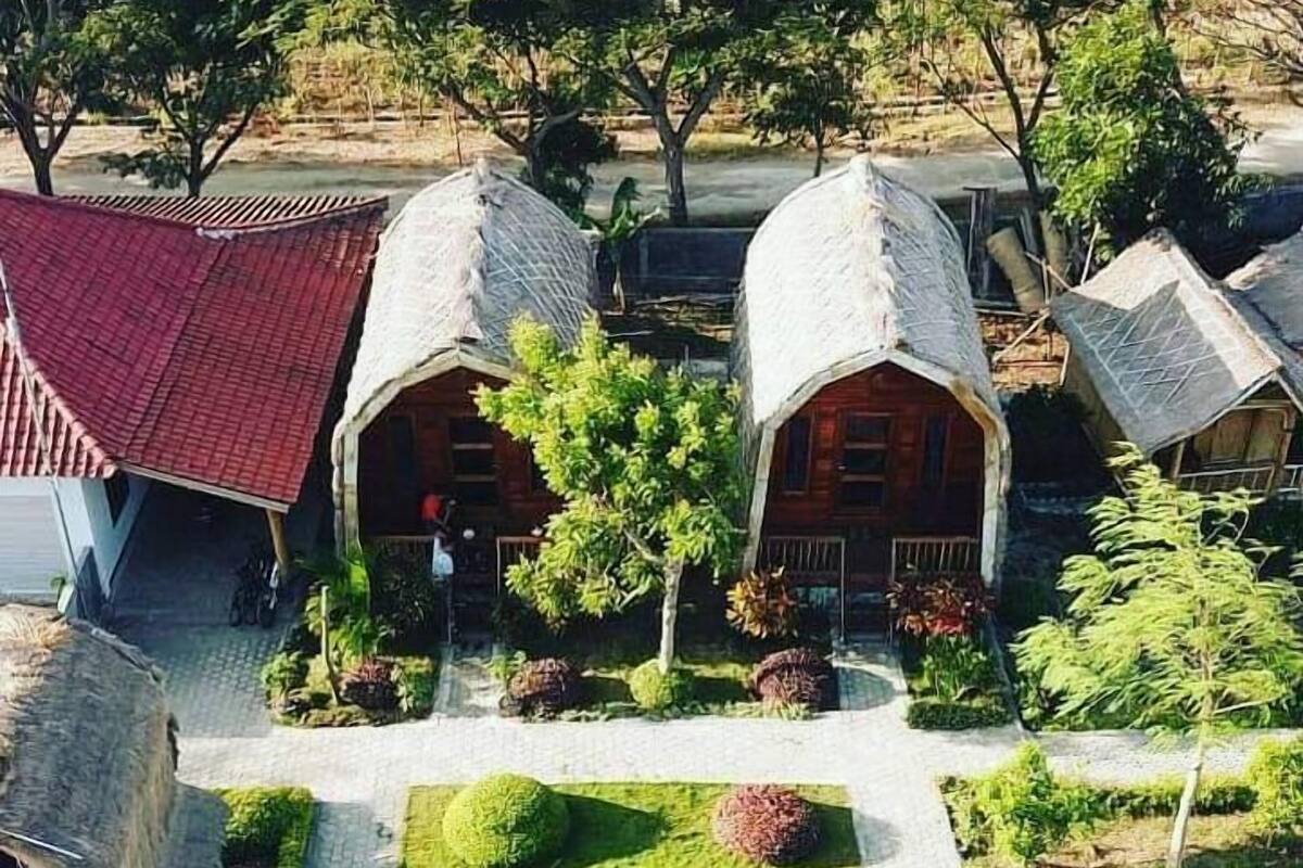 Een traditioneel huis met een pannendak, omgeven door een goed onderhouden tuin met strak gemaaid gras en bolvormige haagbeplanting.