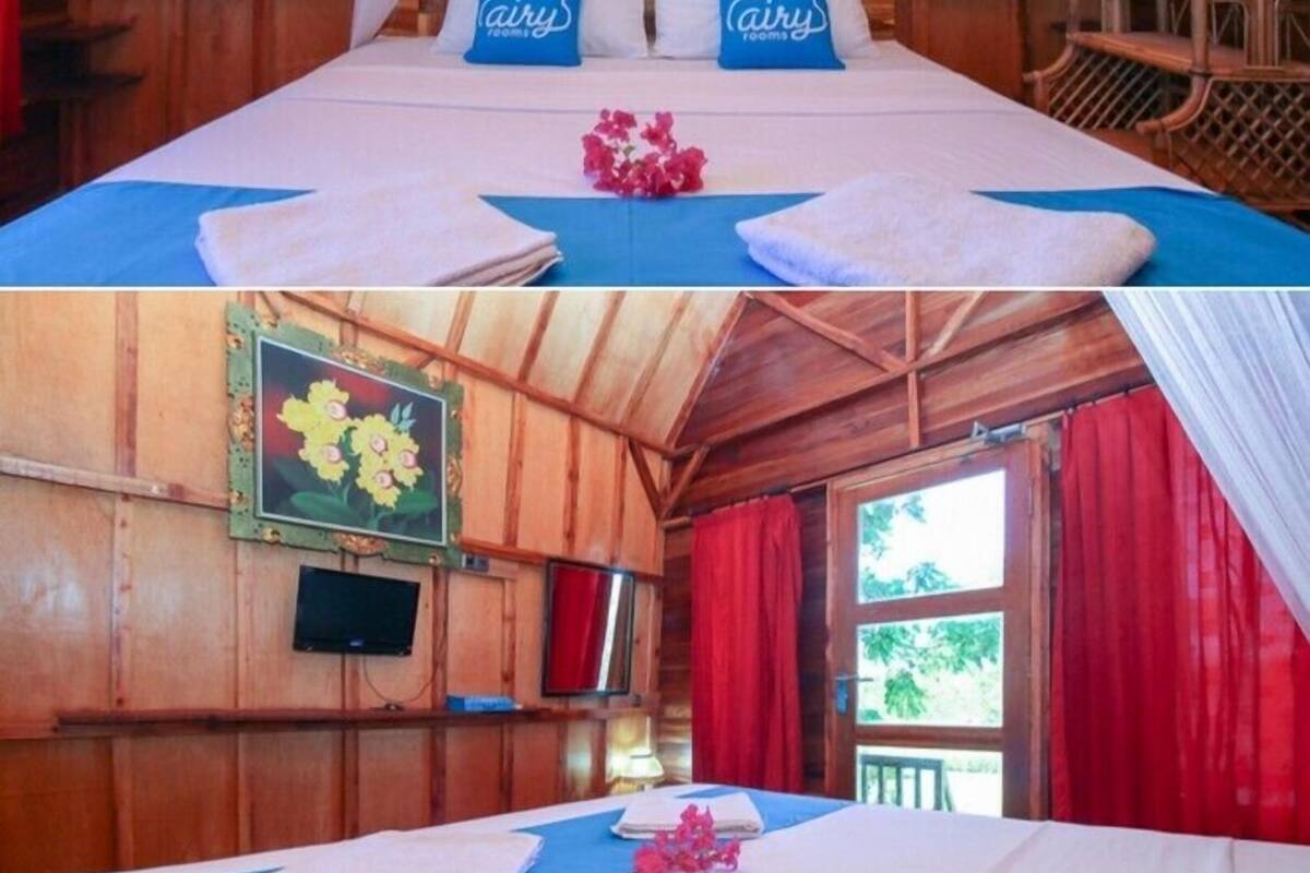 Een houten kamer in blokhutstijl met een bed, een televisie en een raam met rode gordijnen.