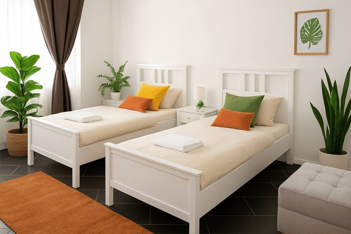 Una habitación con dos camas individuales, una mesita, una silla y plantas en macetas.