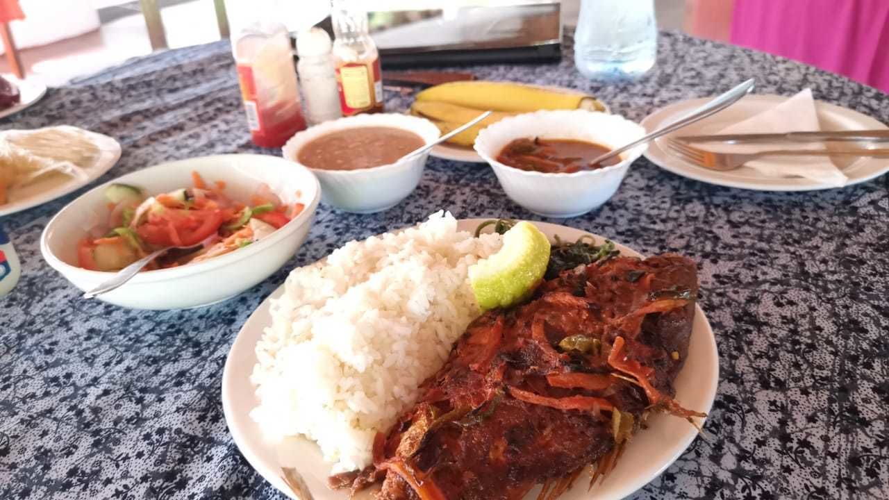 A table with a plate of rice, a fish, and two bowls of sauce.