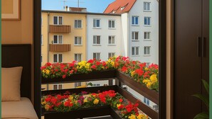Un balcon agrémenté de jardinières, une vue sur des immeubles à étages et une porte donnant sur une pièce.